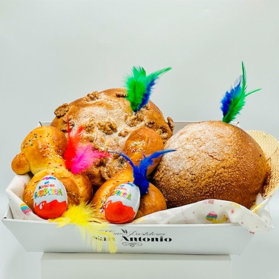 Elegante Pack de Pascua con torta de pasas y nueces, pan quemado y monas con huevo Kinder sobre una bandeja.