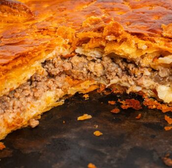 Empanada de carne con hojaldre artesanal y relleno de carne y cebolla.