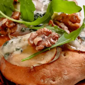 Coca salada gourmet hecha de masa amasada y horneada a mano selección de quesos, pera y nueces.