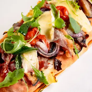 Coca salada gourmet hecha de masa amasada y horneada a mano de jamón ibérico con queso brie.